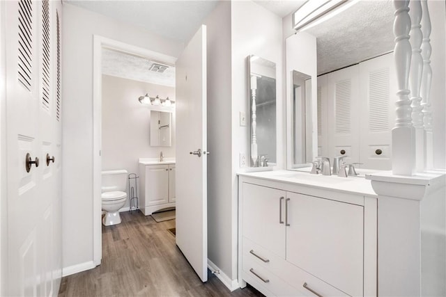 bathroom featuring hardwood / wood-style floors, vanity, toilet, and a textured ceiling