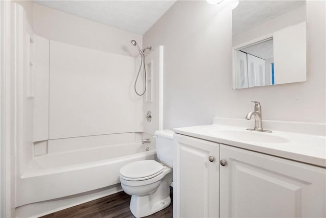 full bathroom featuring wood-type flooring,  shower combination, a textured ceiling, toilet, and vanity