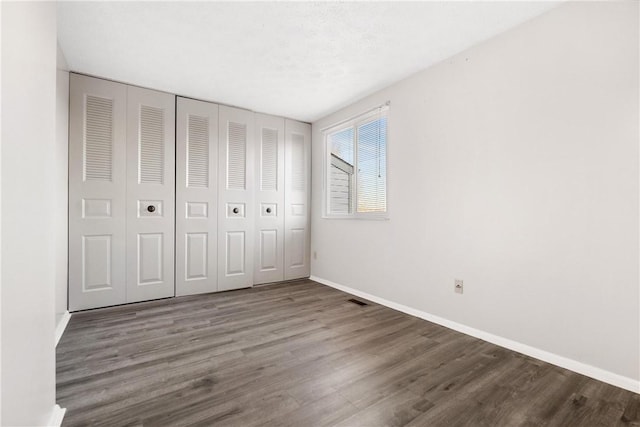 unfurnished bedroom with a textured ceiling and dark wood-type flooring