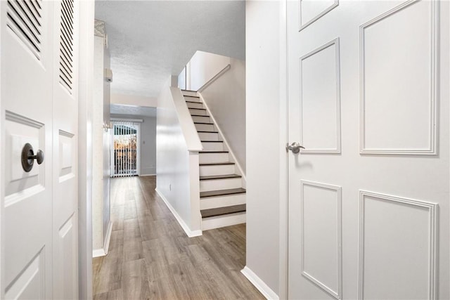 hallway featuring light hardwood / wood-style floors and a textured ceiling