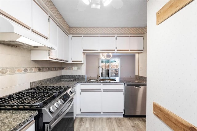 kitchen featuring dark stone counters, sink, light hardwood / wood-style floors, white cabinetry, and stainless steel appliances