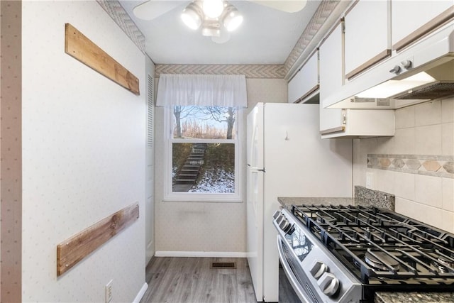 kitchen featuring light wood-type flooring, custom exhaust hood, ceiling fan, white cabinets, and stainless steel gas stove