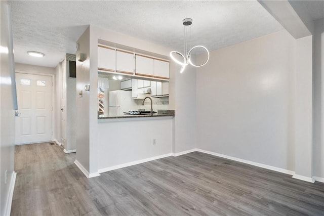 unfurnished dining area with a textured ceiling, dark hardwood / wood-style flooring, and sink