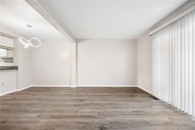 spare room with light hardwood / wood-style floors and a notable chandelier