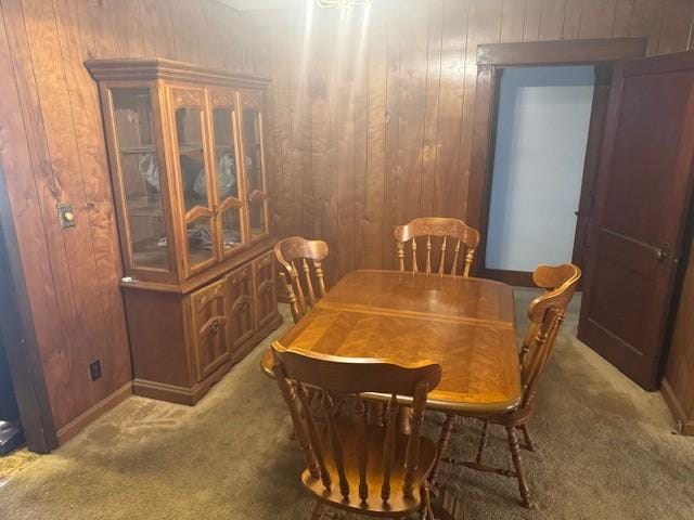 dining room featuring wooden walls and carpet floors