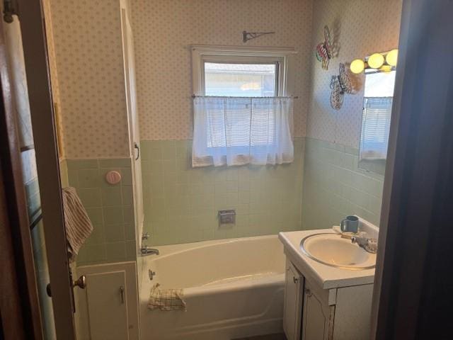 bathroom with a bathing tub, vanity, and tile walls