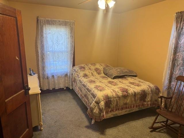 bedroom with ceiling fan and dark colored carpet