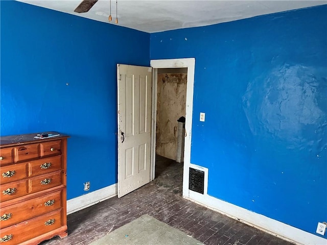 unfurnished bedroom with ceiling fan and dark wood-type flooring