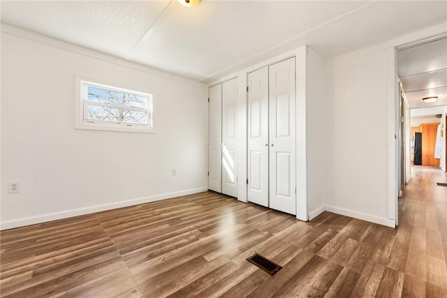 unfurnished bedroom with dark hardwood / wood-style floors and ornamental molding