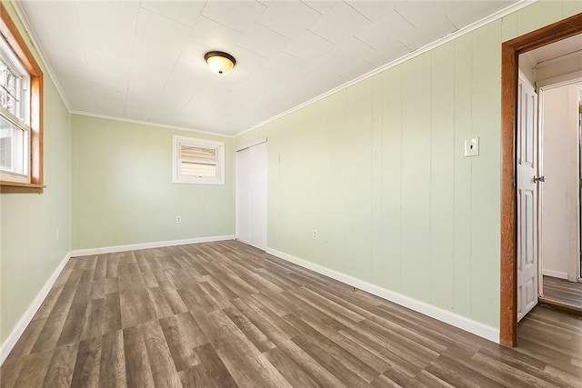 empty room with wood-type flooring and crown molding