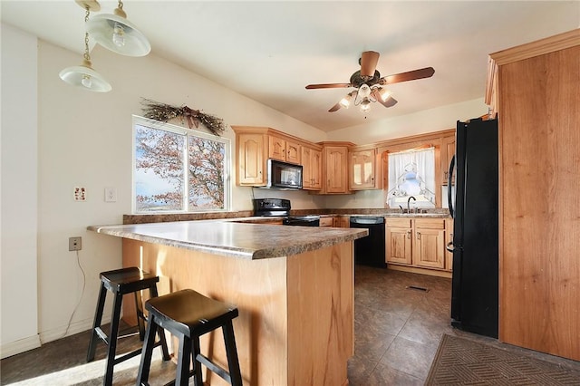 kitchen featuring ceiling fan, a kitchen breakfast bar, kitchen peninsula, black appliances, and dark tile patterned flooring