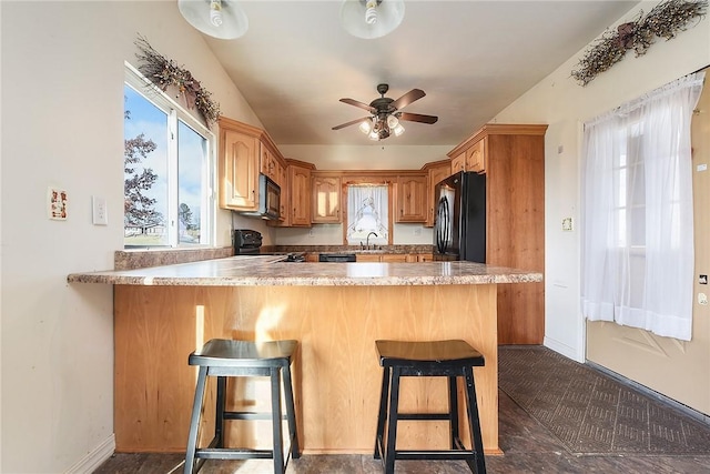 kitchen featuring black appliances, a breakfast bar, ceiling fan, and kitchen peninsula