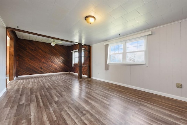 unfurnished room featuring ornamental molding, hardwood / wood-style flooring, and wooden walls