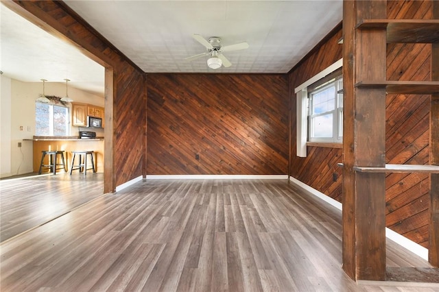 empty room featuring wooden walls, ceiling fan, and hardwood / wood-style flooring