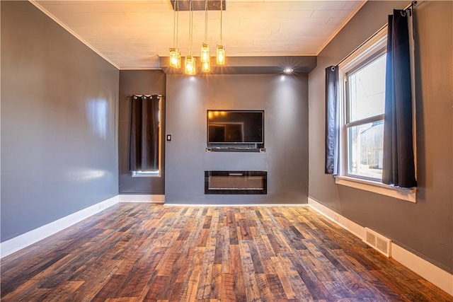 unfurnished living room featuring hardwood / wood-style floors and ornamental molding