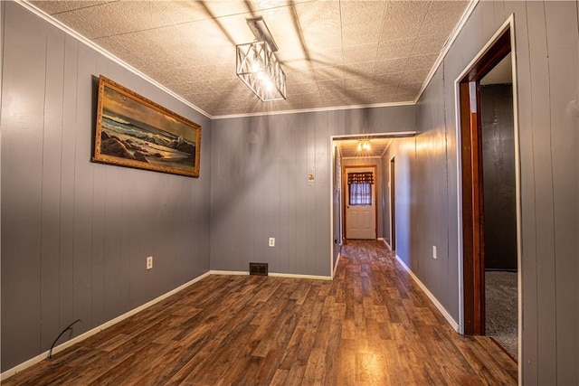 empty room featuring crown molding, dark wood-type flooring, and wood walls