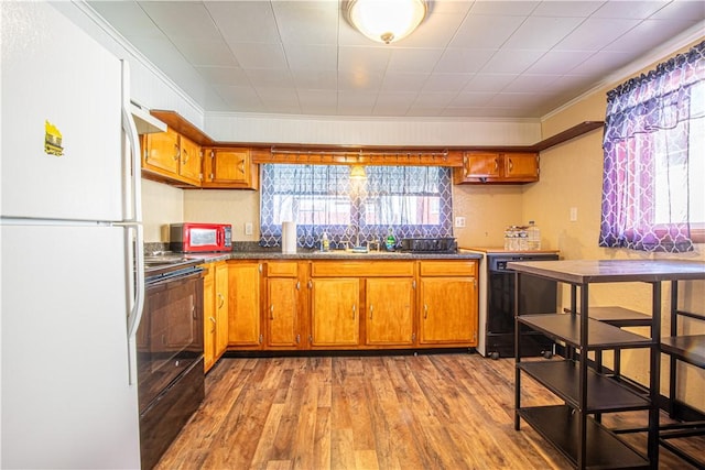 kitchen featuring sink, light hardwood / wood-style flooring, black appliances, and ornamental molding