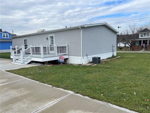 rear view of property featuring central AC, a deck, and a lawn