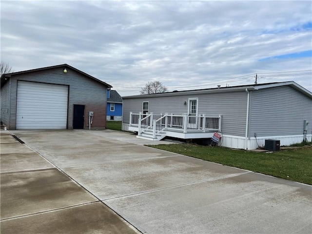 rear view of property featuring an outdoor structure, a wooden deck, cooling unit, a yard, and a garage