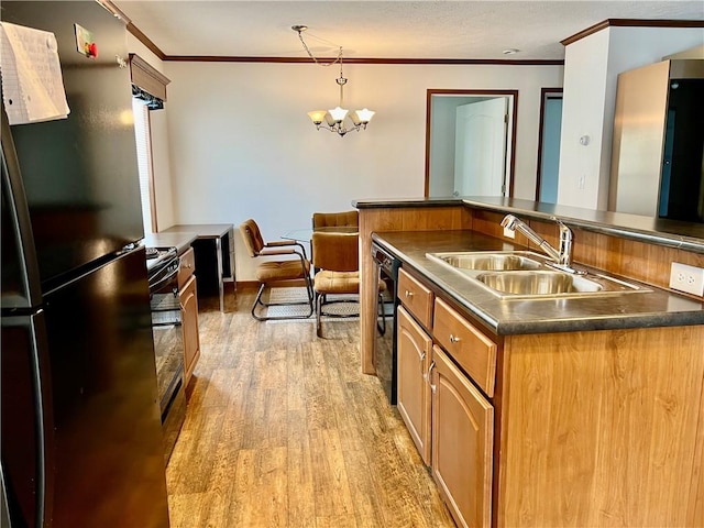 kitchen featuring sink, black appliances, decorative light fixtures, light hardwood / wood-style floors, and an island with sink