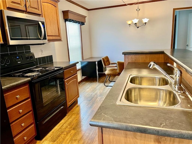 kitchen with sink, black range oven, an inviting chandelier, light hardwood / wood-style floors, and ornamental molding