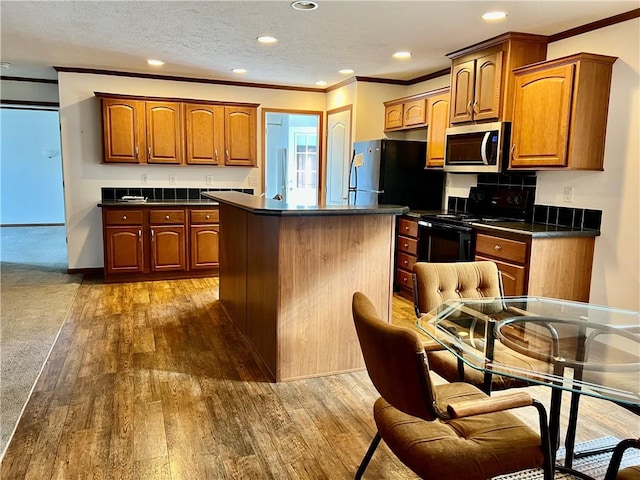 kitchen featuring dark hardwood / wood-style flooring, a kitchen island, crown molding, and black appliances