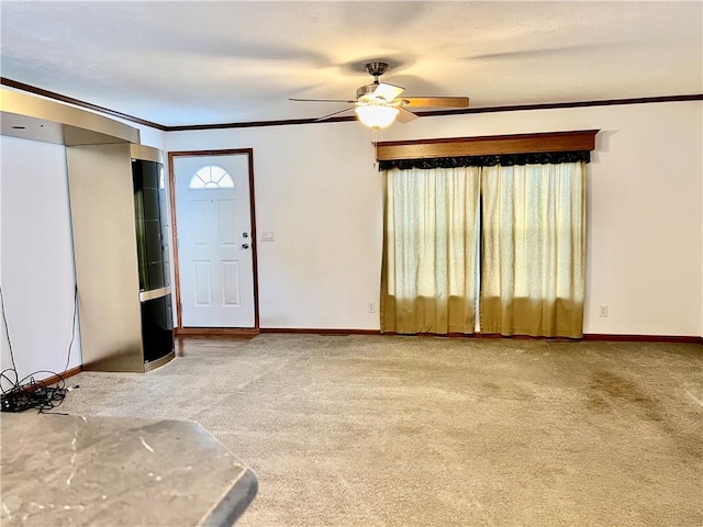 carpeted entrance foyer with ceiling fan and ornamental molding