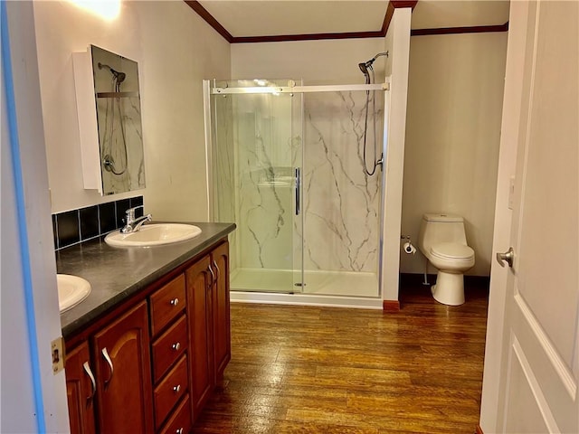 bathroom with vanity, crown molding, wood-type flooring, toilet, and a shower with shower door