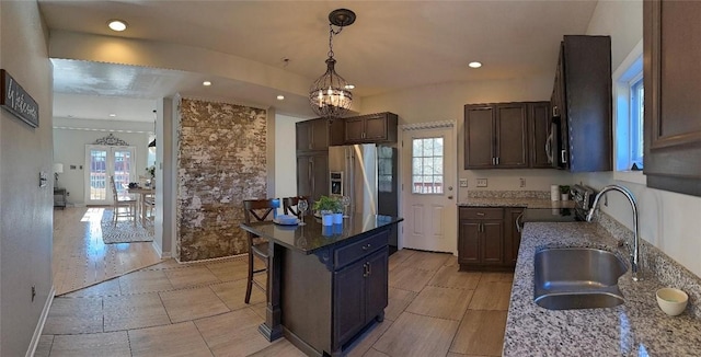 kitchen featuring stainless steel fridge with ice dispenser, stone counters, a center island, and a healthy amount of sunlight