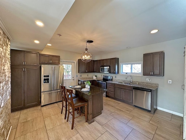 kitchen with a healthy amount of sunlight, hanging light fixtures, a kitchen island, and stainless steel appliances