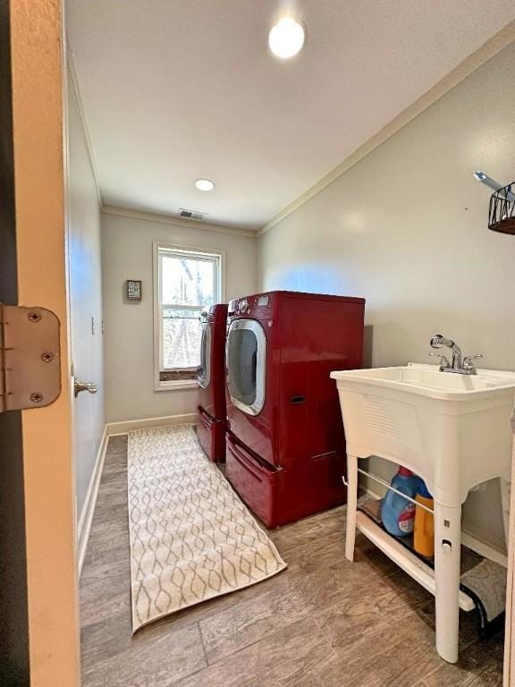 washroom featuring wood-type flooring, washing machine and dryer, and crown molding