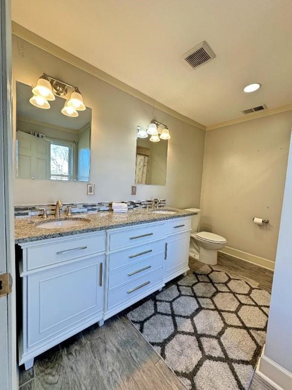 bathroom featuring hardwood / wood-style flooring, vanity, toilet, and ornamental molding