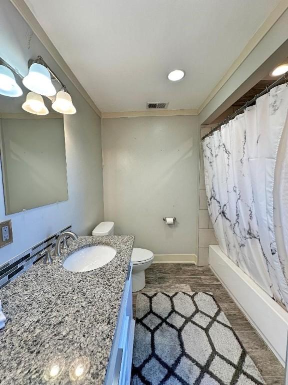 full bathroom with crown molding, toilet, vanity, shower / tub combo, and hardwood / wood-style flooring