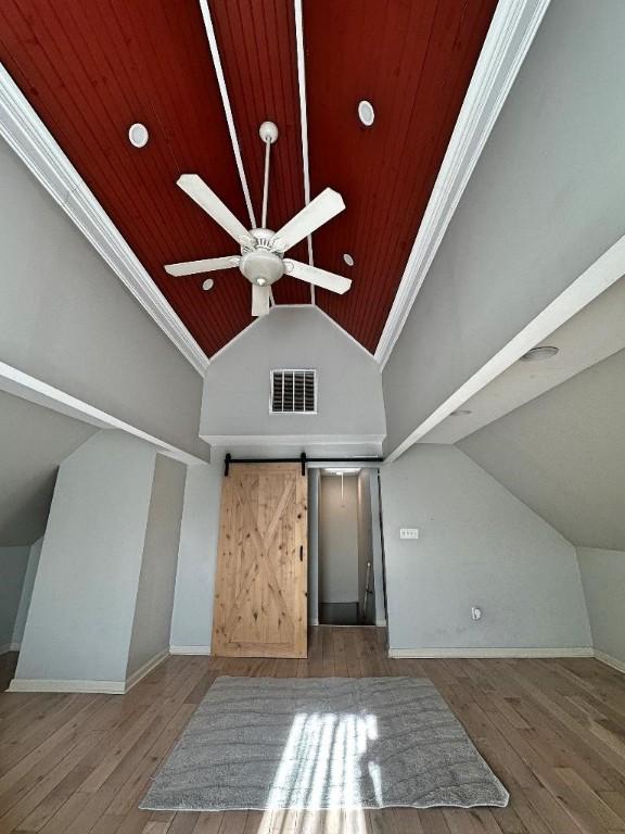 bonus room with a barn door, hardwood / wood-style flooring, ceiling fan, and lofted ceiling