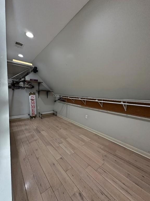 walk in closet with light wood-type flooring and lofted ceiling