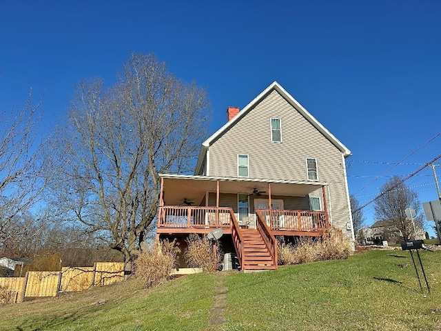 rear view of house featuring ceiling fan, a wooden deck, and a lawn