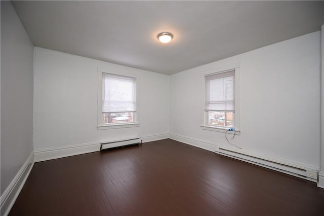 spare room featuring plenty of natural light, baseboard heating, and dark wood-type flooring