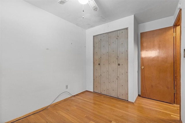 unfurnished bedroom featuring ceiling fan, a closet, and light hardwood / wood-style flooring