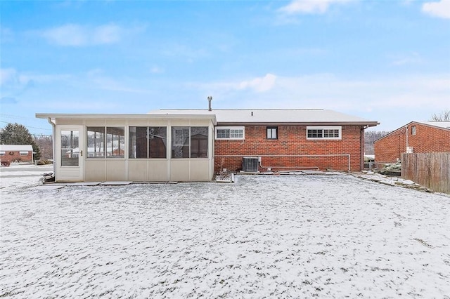 snow covered property featuring a sunroom and central AC unit