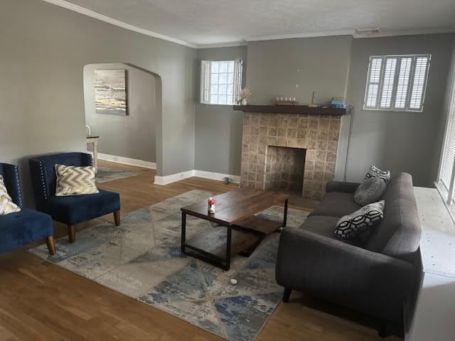 living room with hardwood / wood-style flooring, ornamental molding, and a fireplace