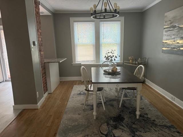 dining space with hardwood / wood-style flooring, crown molding, and a notable chandelier