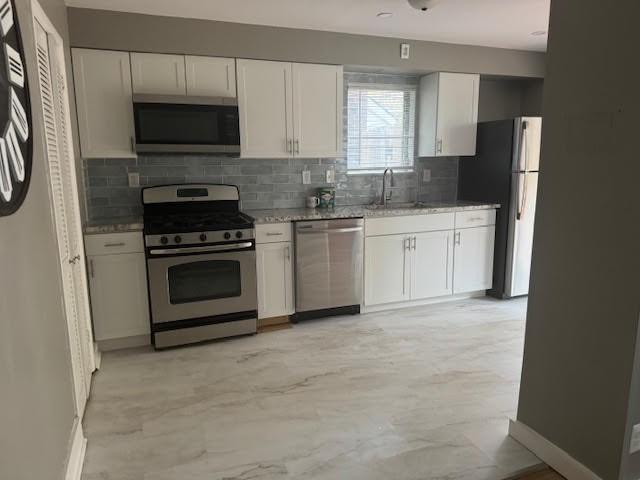 kitchen featuring white cabinets, decorative backsplash, sink, and appliances with stainless steel finishes