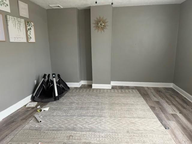 unfurnished room with wood-type flooring and a textured ceiling