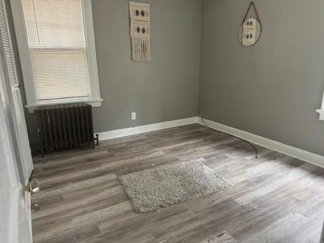 unfurnished room with hardwood / wood-style flooring and radiator