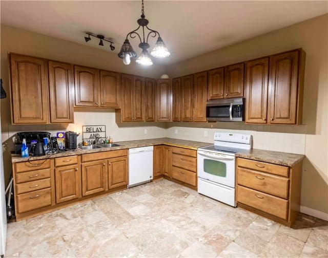 kitchen with white appliances, hanging light fixtures, and sink