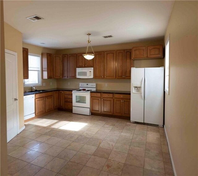 kitchen with pendant lighting, white appliances, light tile patterned floors, and sink