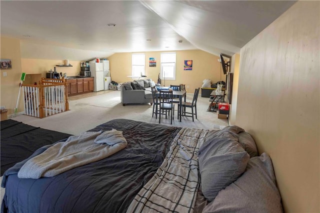 bedroom with white refrigerator, lofted ceiling, and light carpet