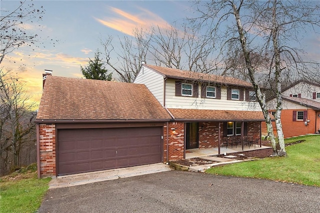 view of front property featuring a porch, a garage, and a yard