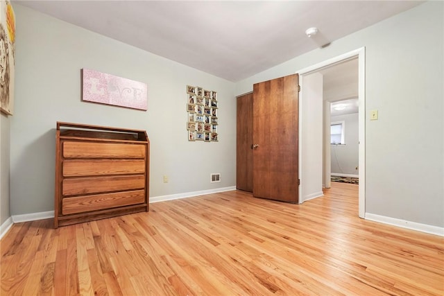 unfurnished bedroom featuring light hardwood / wood-style floors and lofted ceiling