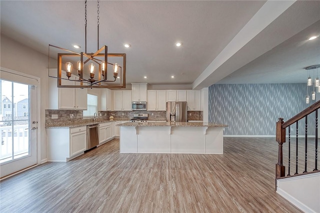 kitchen with white cabinetry, a kitchen island, pendant lighting, and appliances with stainless steel finishes